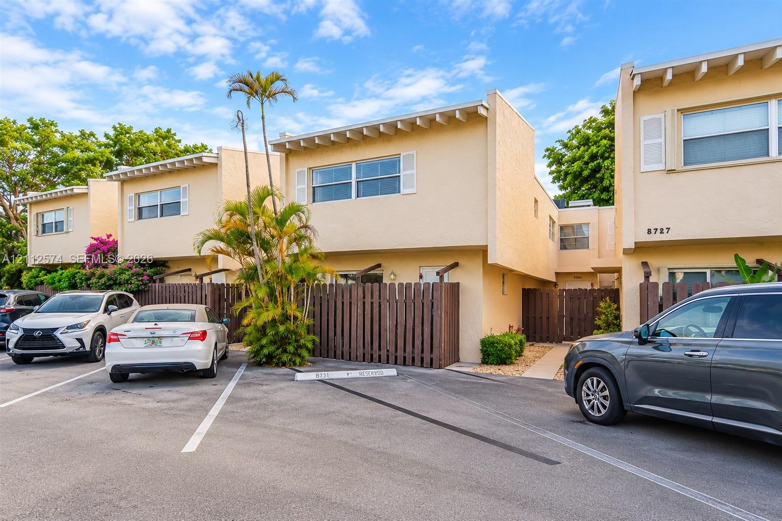 Stucco exterior featuring exposed rafter tails, horizontal wood fencing, and designated parking space