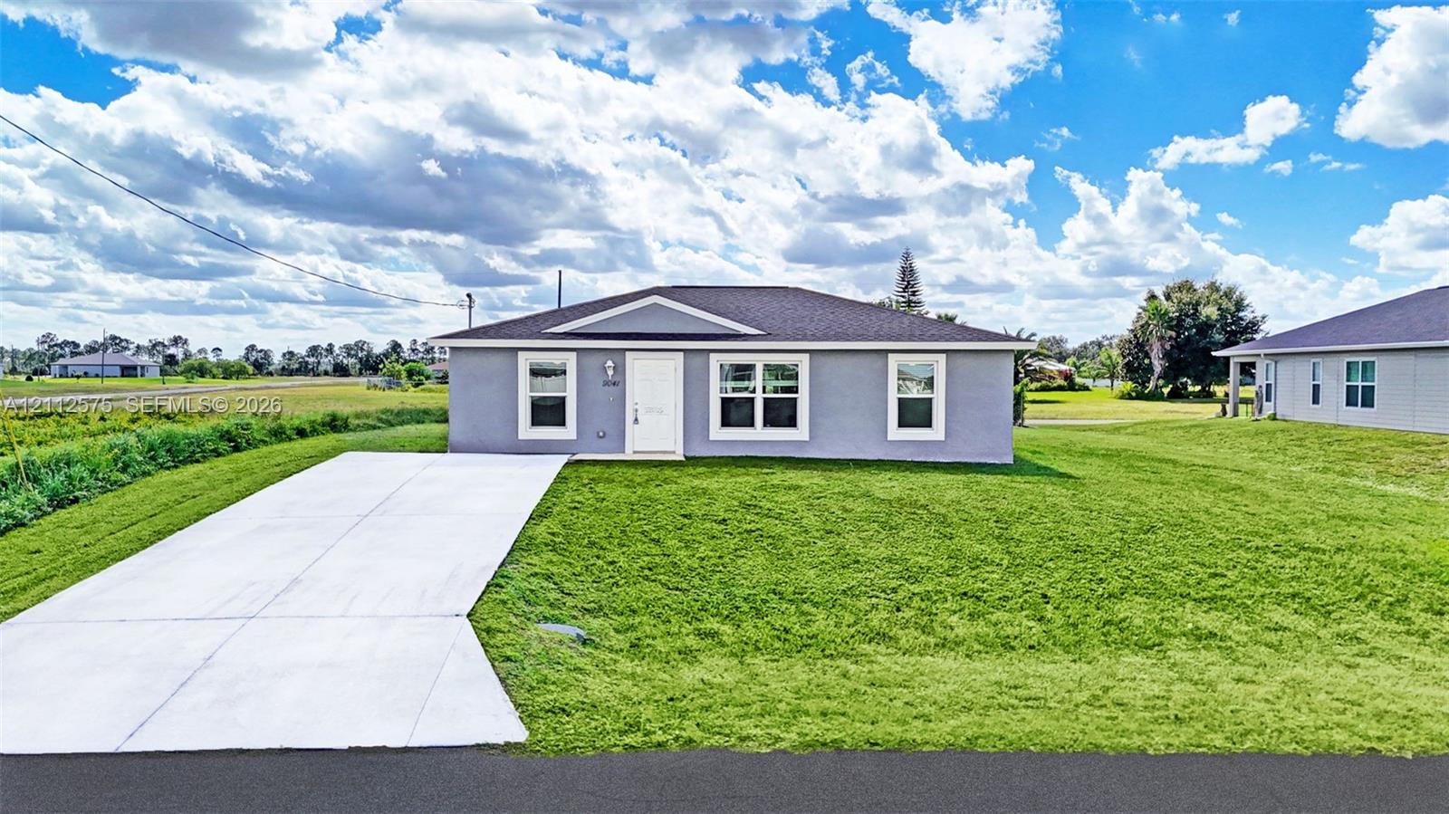 Single-story residence featuring a stucco exterior, hipped roof with asphalt shingles, white-trimmed windows, and a concrete driveway