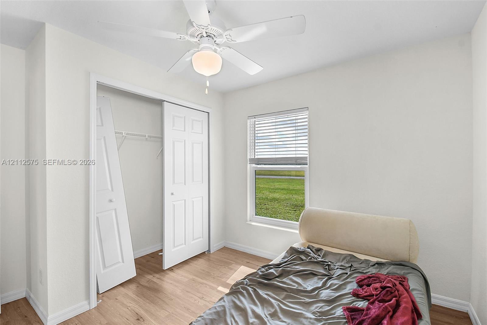 Wood-finish flooring, ceiling fan with integrated lighting, closet with double doors, and horizontal window blinds