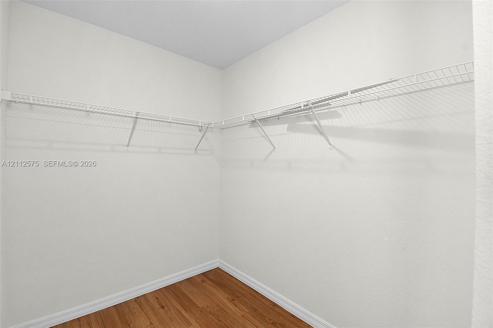 Walk-in storage area featuring wood-finish flooring and wall-mounted white wire shelving