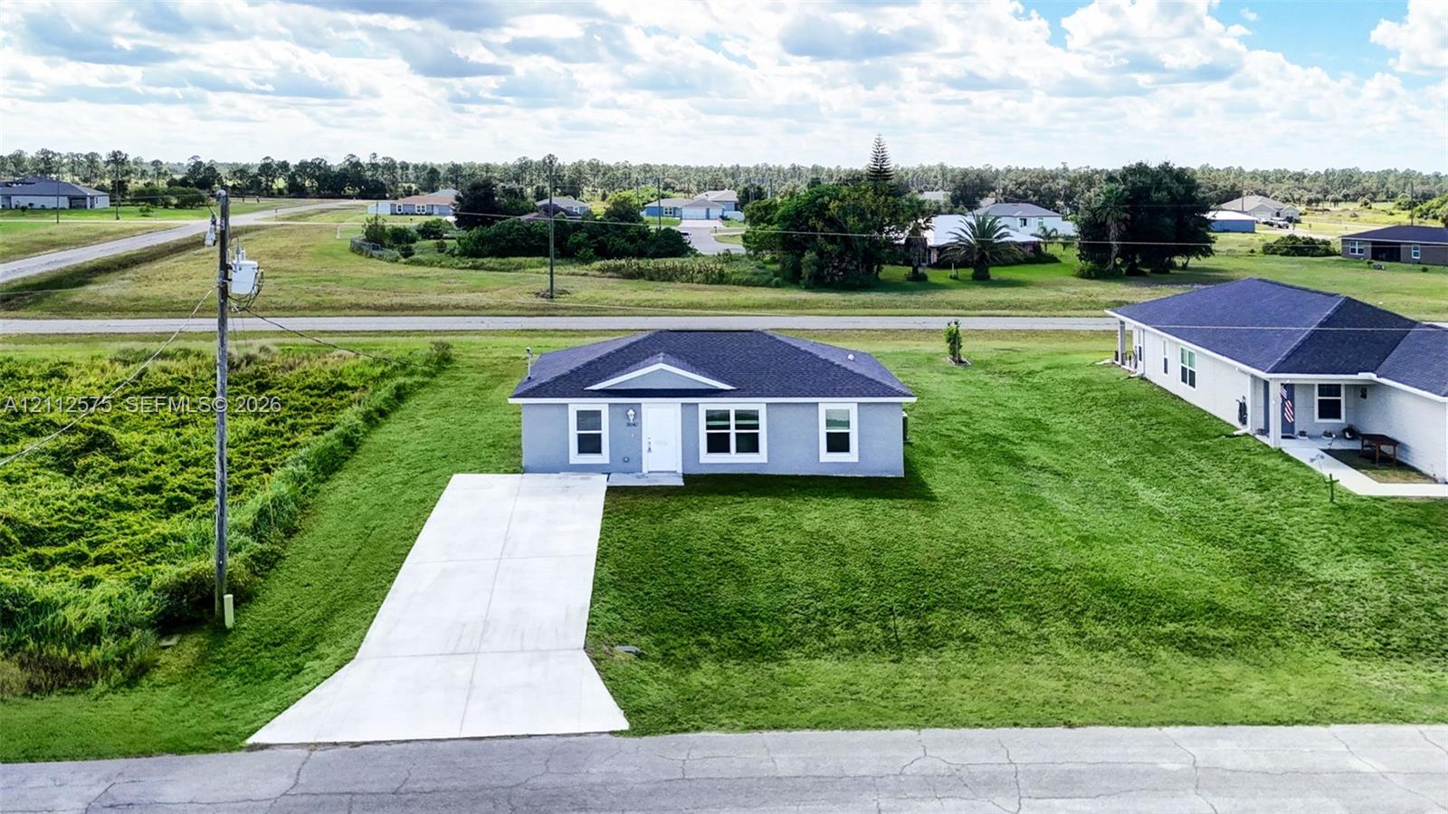 Single-story residence featuring a gray exterior, dark shingle roof, white window trim, and a concrete driveway