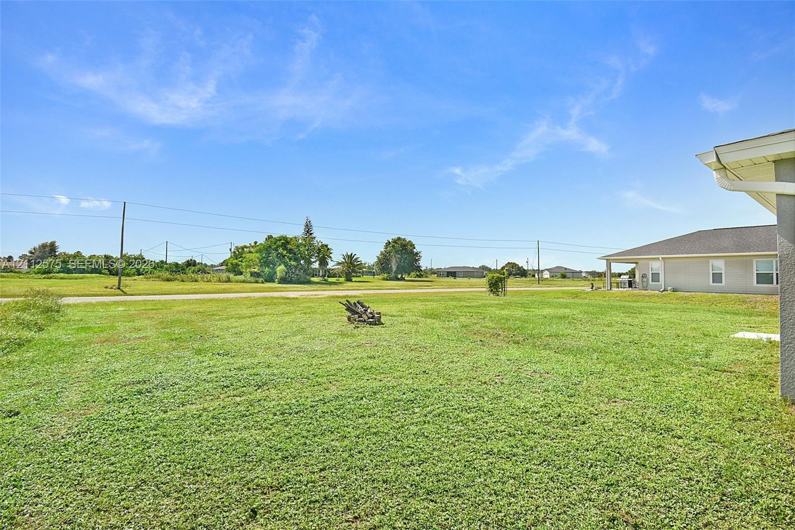 Expansive grass yard featuring open terrain and mature trees