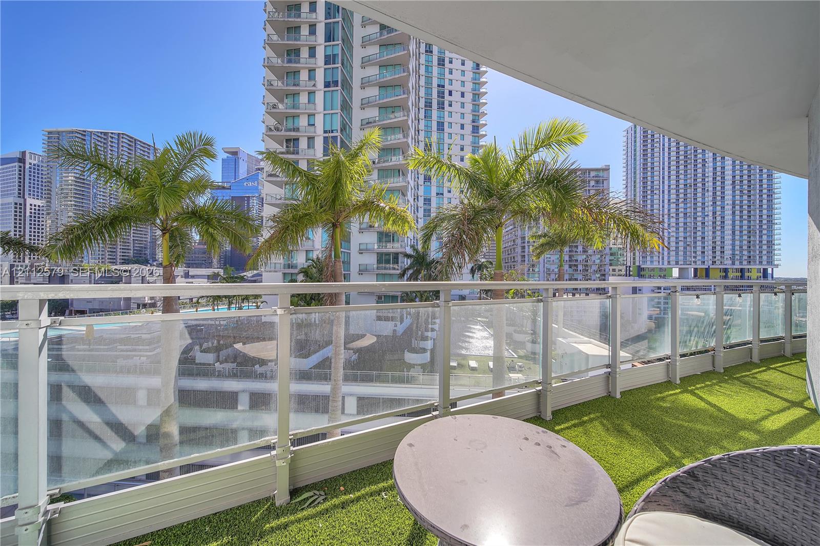 Covered balcony with artificial turf flooring and a transparent glass railing Covered balcony with artificial turf flooring and a transparent glass railing