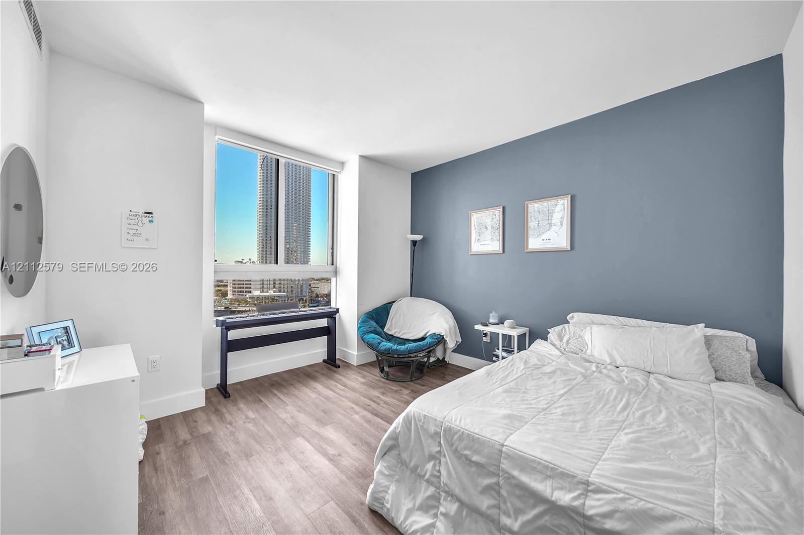 Room featuring wood-finish flooring, a neutral color palette, a blue accent wall, and a large window
