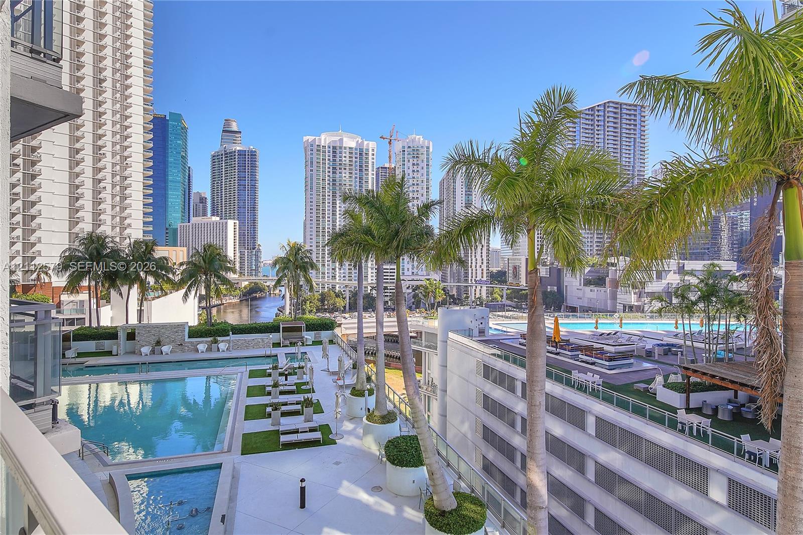 Outdoor terrace featuring a swimming pool, integrated landscaping with palm trees, and panoramic city skyline scenery Outdoor terrace featuring a swimming pool, integrated landscaping with palm trees, and panoramic city skyline scenery