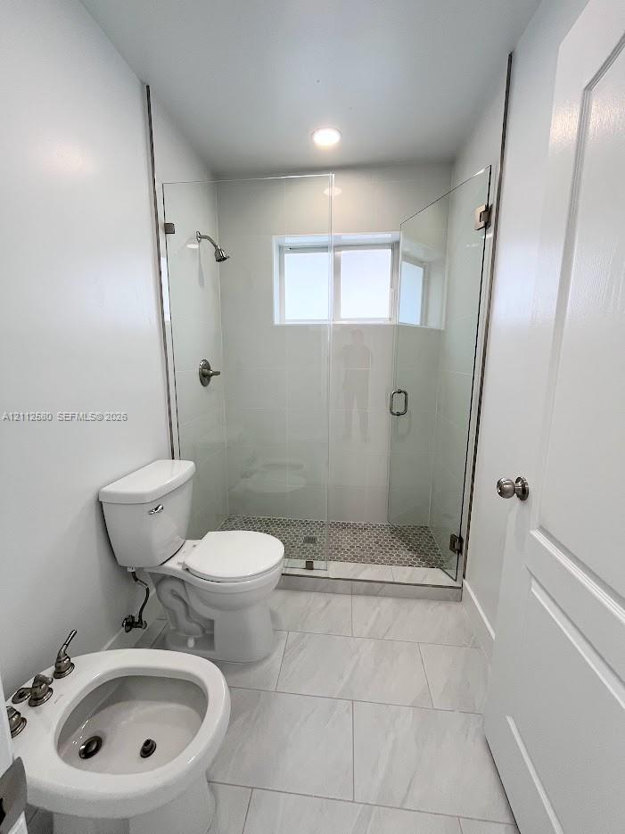 Walk-in shower featuring a frameless glass enclosure, patterned tile flooring, and metallic fixtures