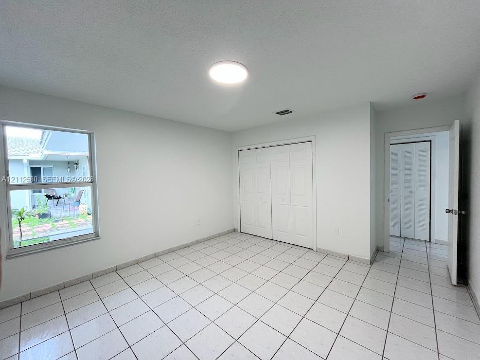 Interior space featuring neutral wall tones, large-format ceramic tile flooring, dual-panel closet doors, and a double-hung window