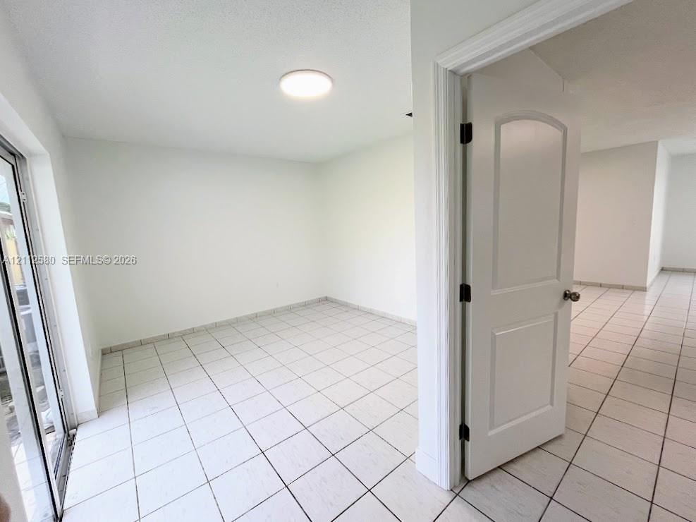 Interior room featuring ceramic tile flooring, a multi-panel arched interior door, a flush-mount ceiling light fixture, and a glass-paned door