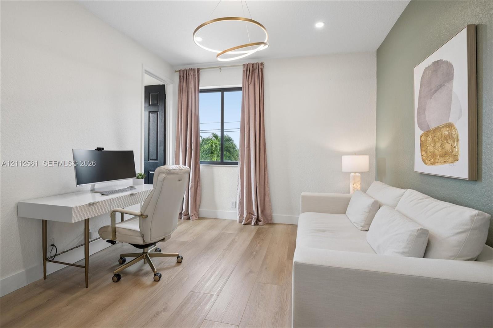 Room featuring wood-finish flooring, a modern circular LED light fixture, a singular window, and an accent wall