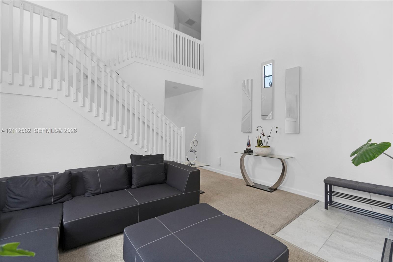 Two-story foyer featuring high ceilings, open-railing staircase, and polished tile flooring