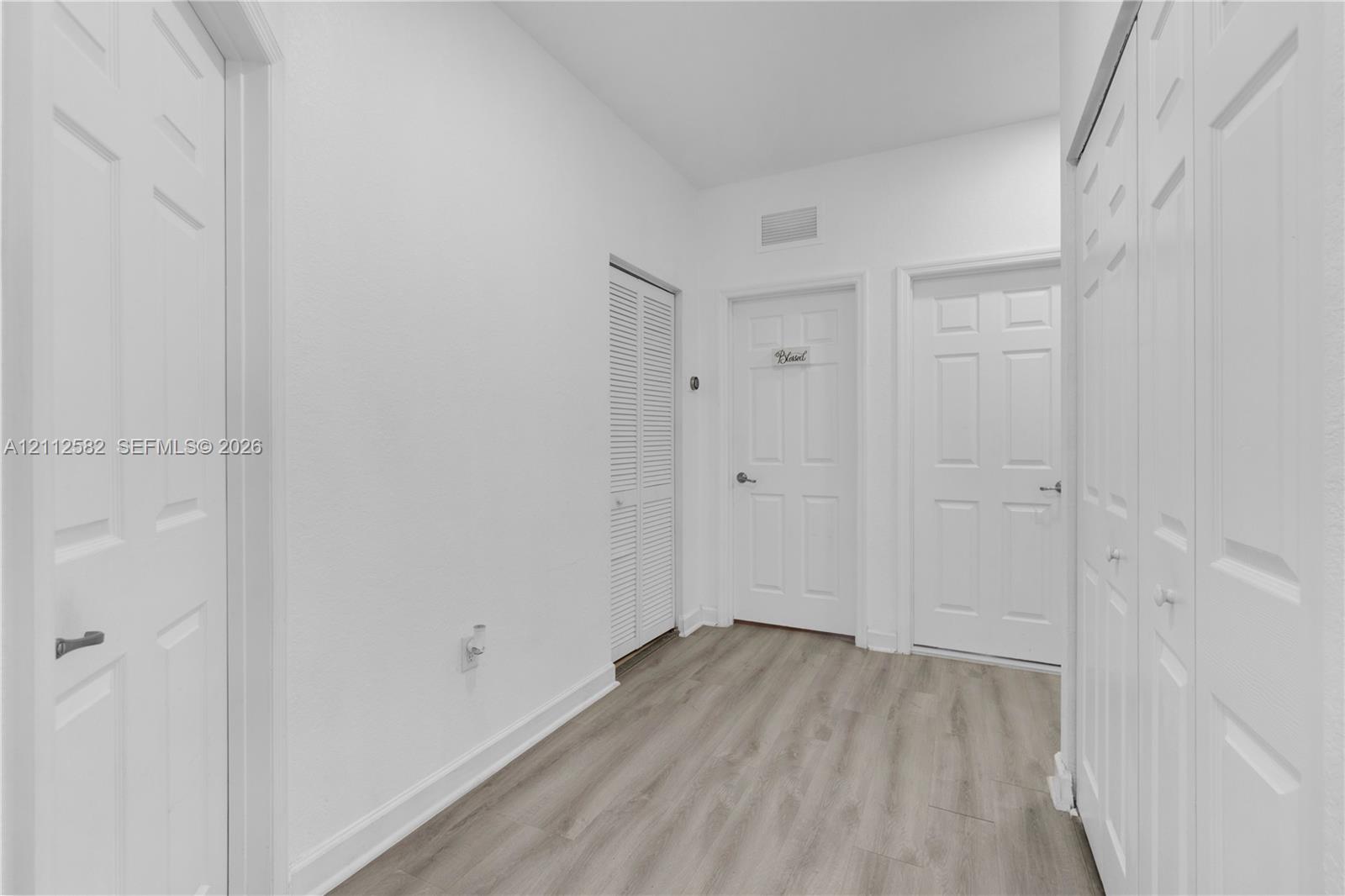 Interior hall featuring wood-finish flooring, two sets of bifold closet doors, and panel-style interior doors