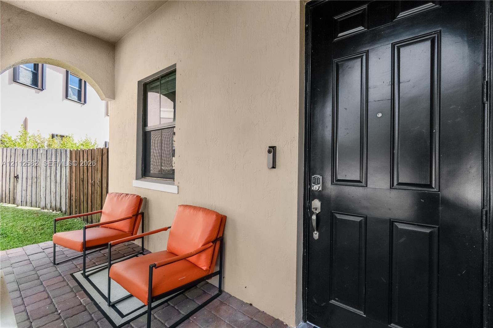 Covered entryway featuring a paver patio, arched ceiling detail, and a paneled entry door with hardware Covered entryway featuring a paver patio, arched ceiling detail, and a paneled entry door with hardware
