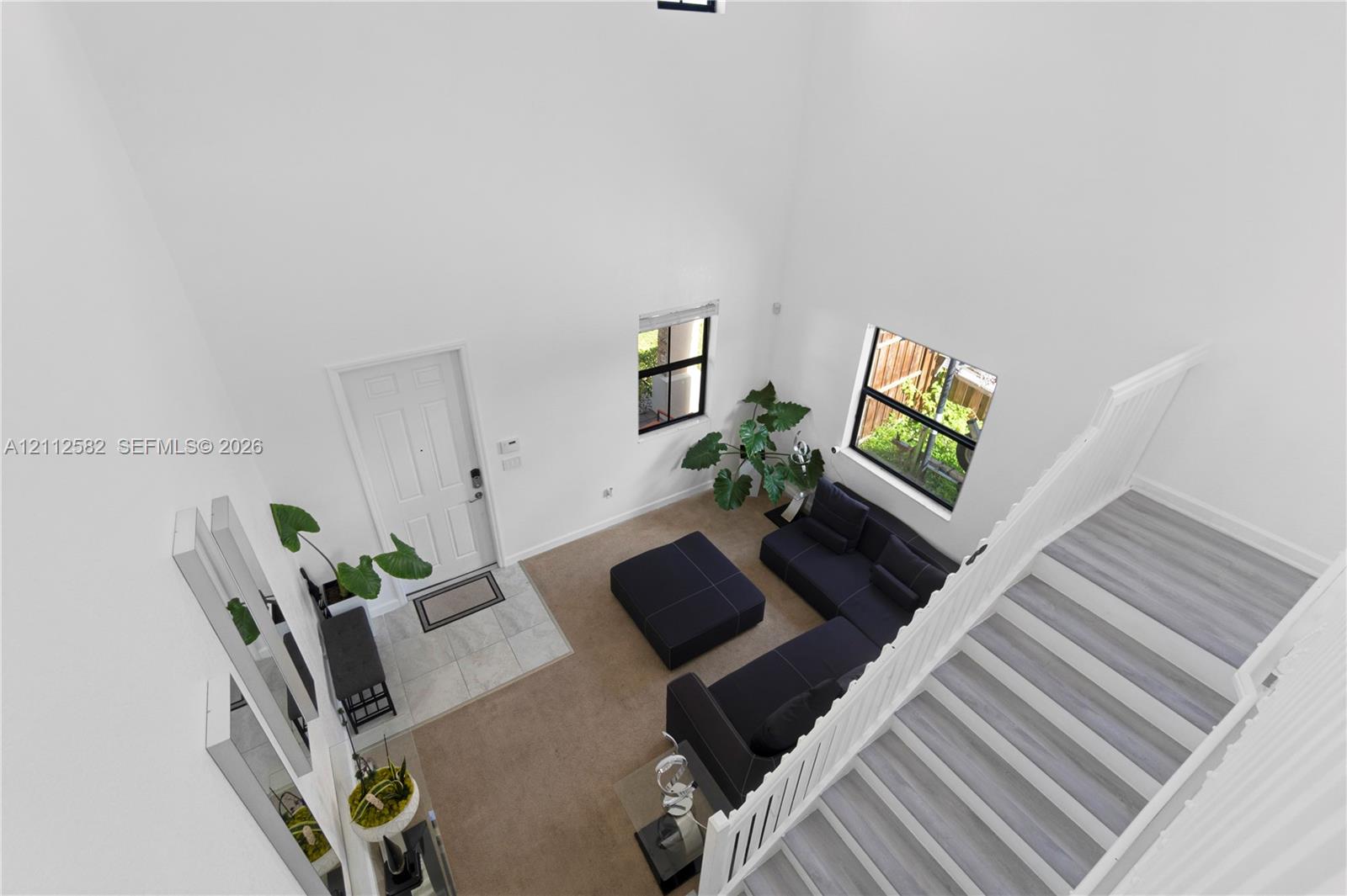High-ceilinged entry featuring a white paneled door with tile flooring, wood-finish staircase treads, and white vertical balusters