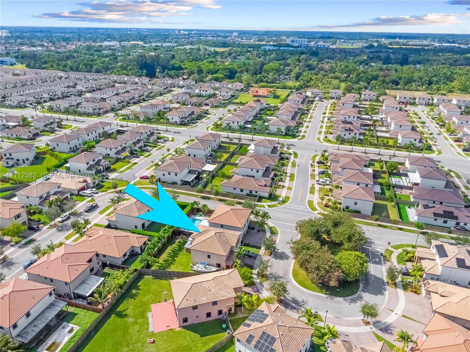 Aerial perspective of a two-story residence featuring a tiled roof, integrated swimming pool, fenced rear yard, and paved driveway