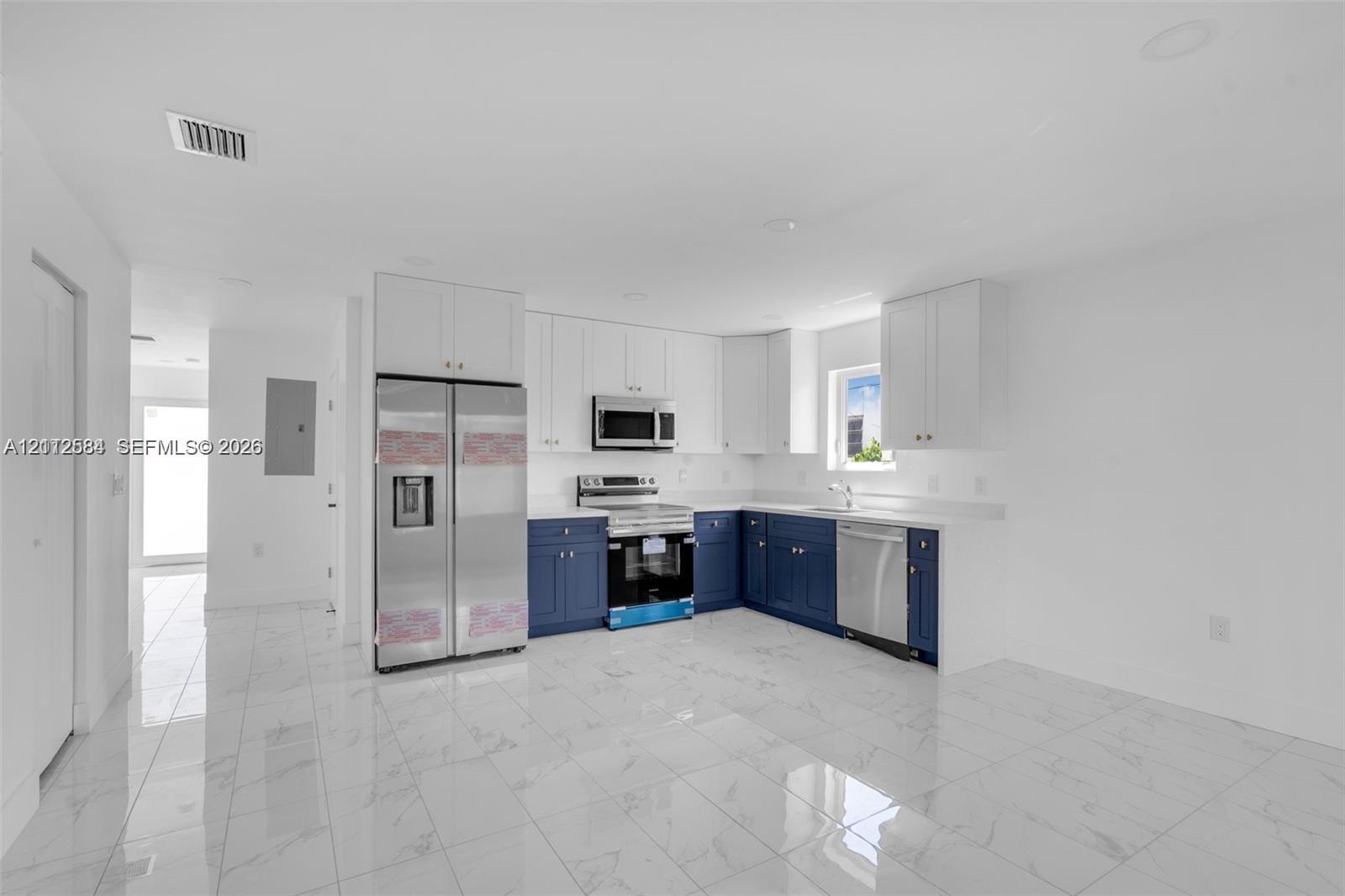 Kitchen featuring two-tone cabinetry, stainless steel appliances, quartz countertops, and white tile flooring