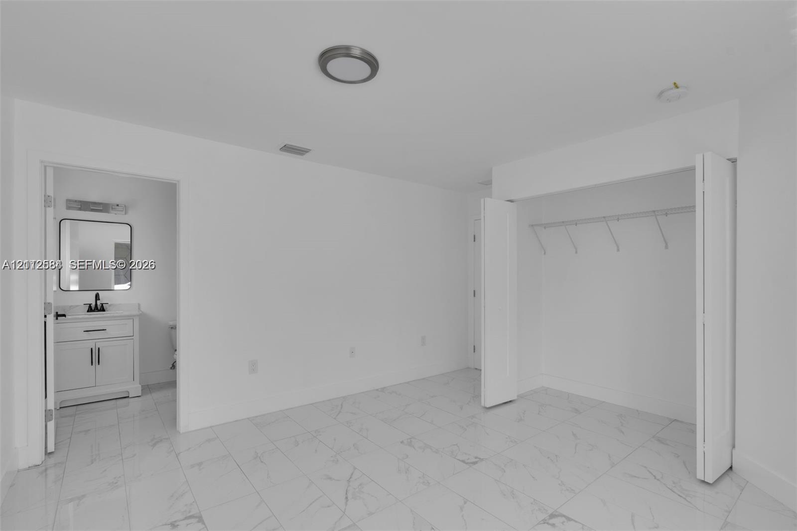 Interior space featuring stone-finish tile flooring, a walk-in closet with built-in shelving, and a dual-door entry