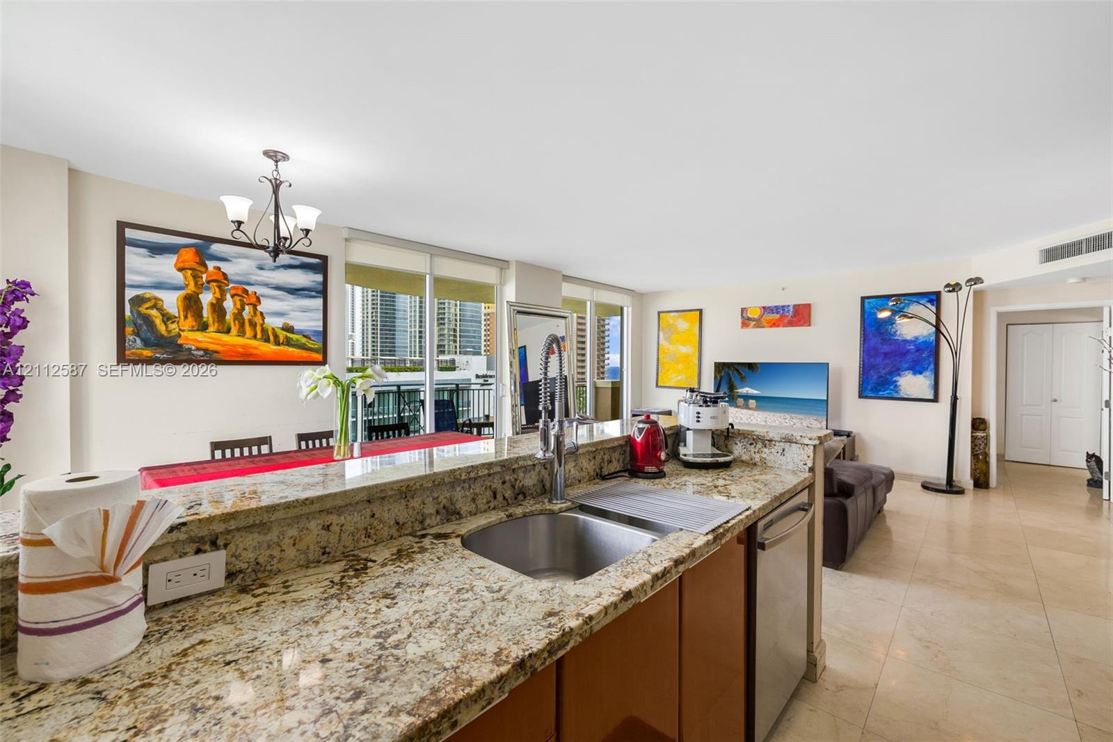 Kitchen featuring natural stone countertops, stainless steel undermount sink with arched pull-down faucet, stainless steel dishwasher, and tile flooring