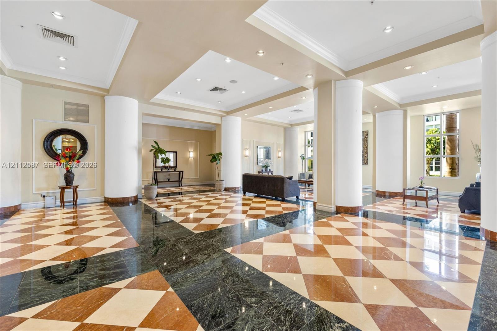 Grand foyer featuring geometric patterned stone flooring, recessed ceiling lighting, and structural circular columns