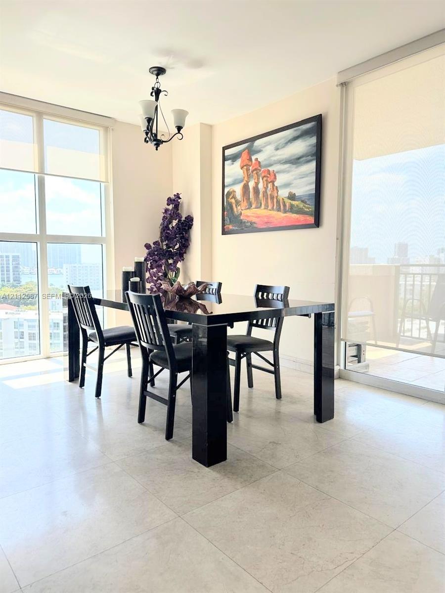Floor-to-ceiling windows, light-toned tile flooring, and a multi-arm metal chandelier