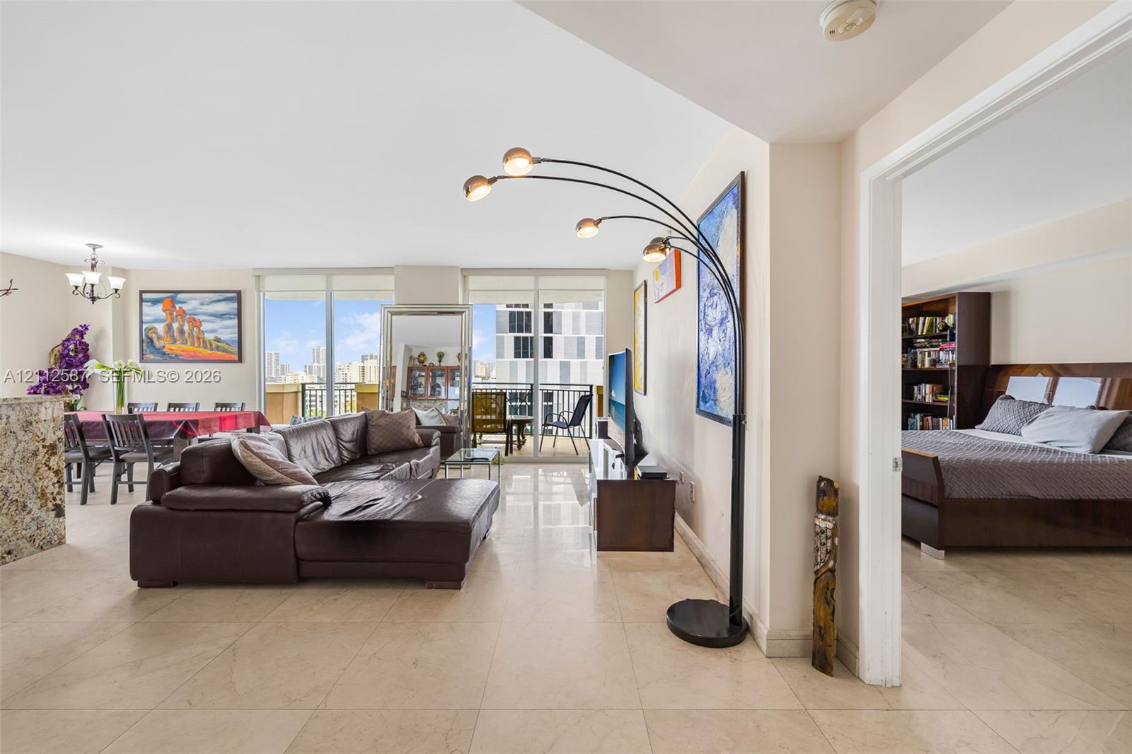 Large-format stone tile flooring, expansive floor-to-ceiling windows, and private exterior balcony access