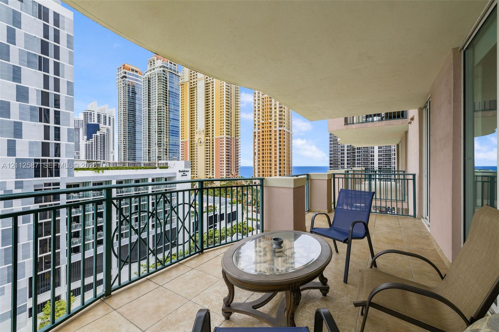 Covered balcony featuring tile flooring and decorative metal railings with urban and coastal scenery