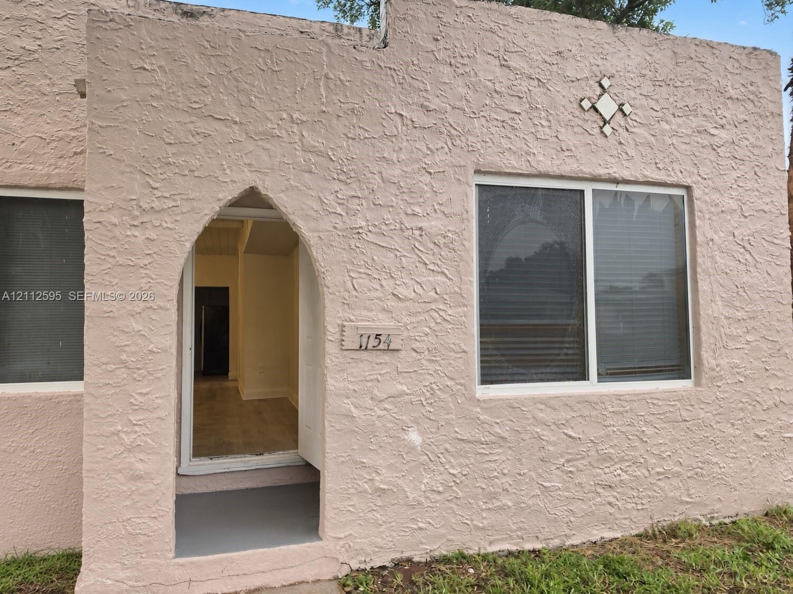 Stucco exterior featuring a pointed arch entryway, decorative diamond-shaped wall accent, and double-pane windows