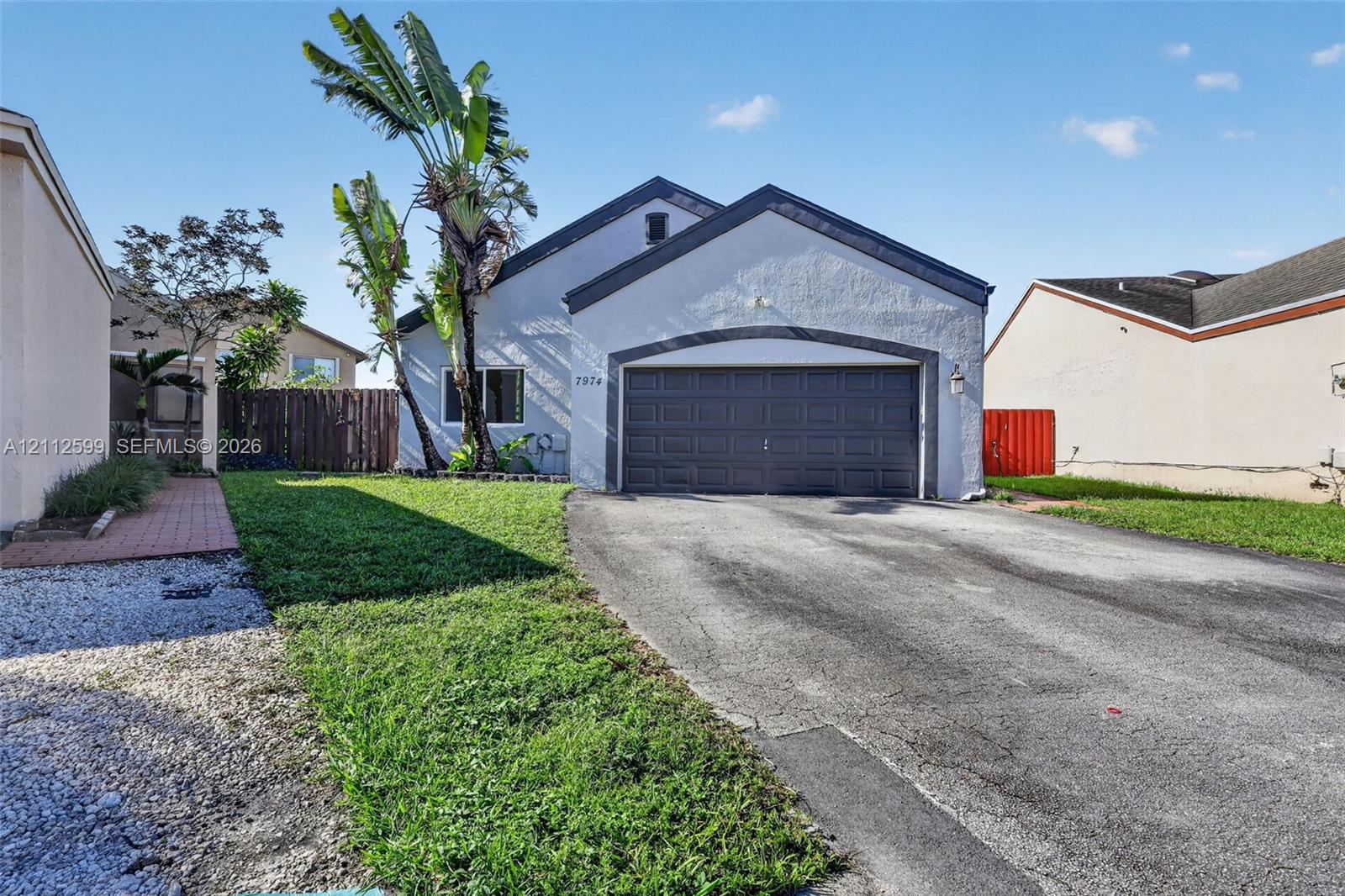Stucco exterior featuring a dual-gabled roofline, an attached two-car garage, and a paved driveway