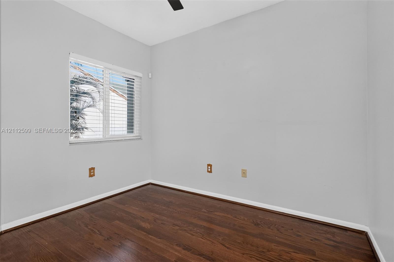 Room featuring wood-finish flooring, neutral wall paint, and a window with horizontal blinds