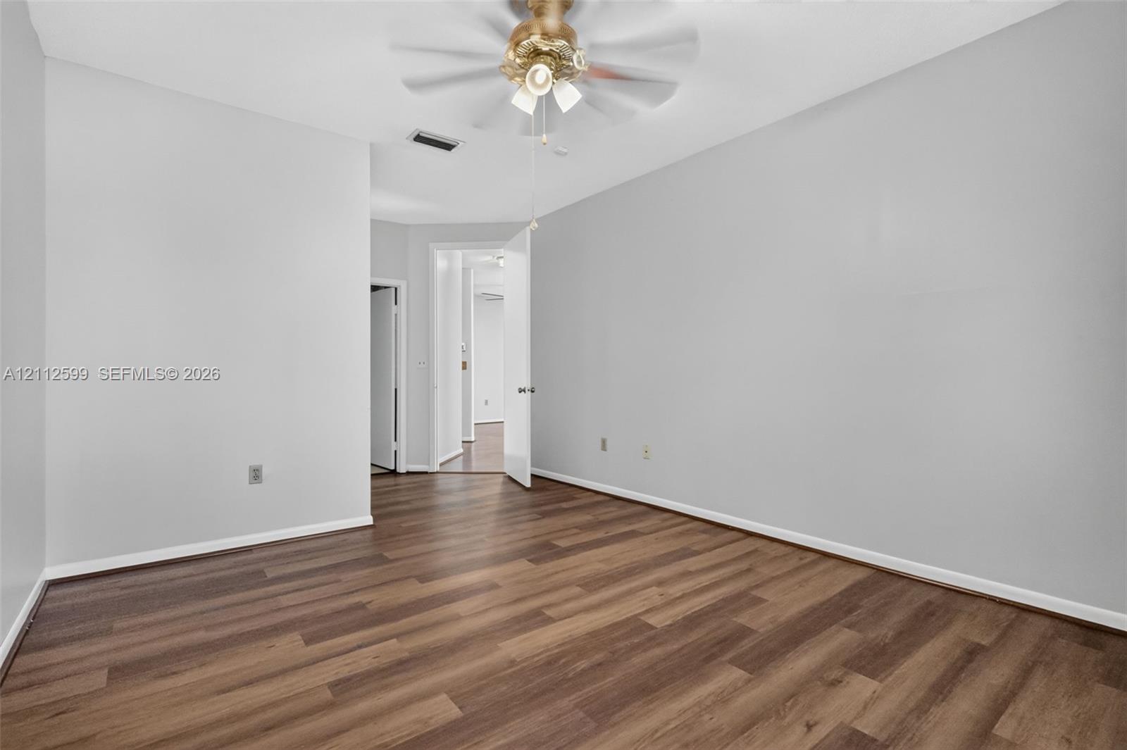 Neutral interior space featuring wood-finish flooring and a multi-light ceiling fan