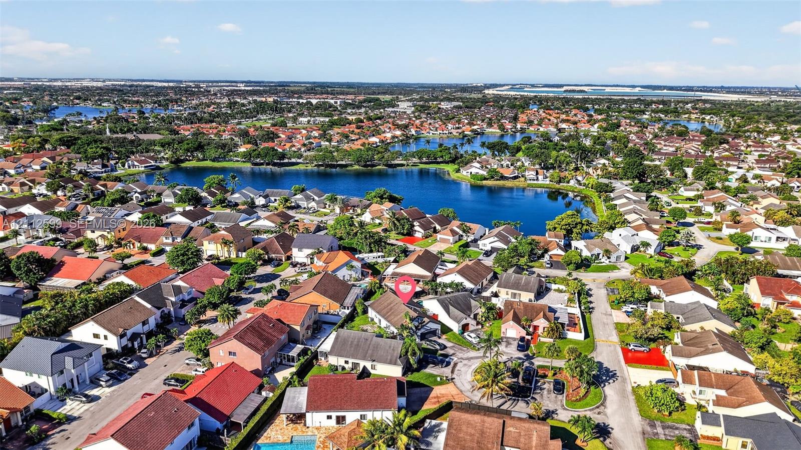 Aerial perspective of a suburban lot featuring mature palm trees and direct proximity to a community lake