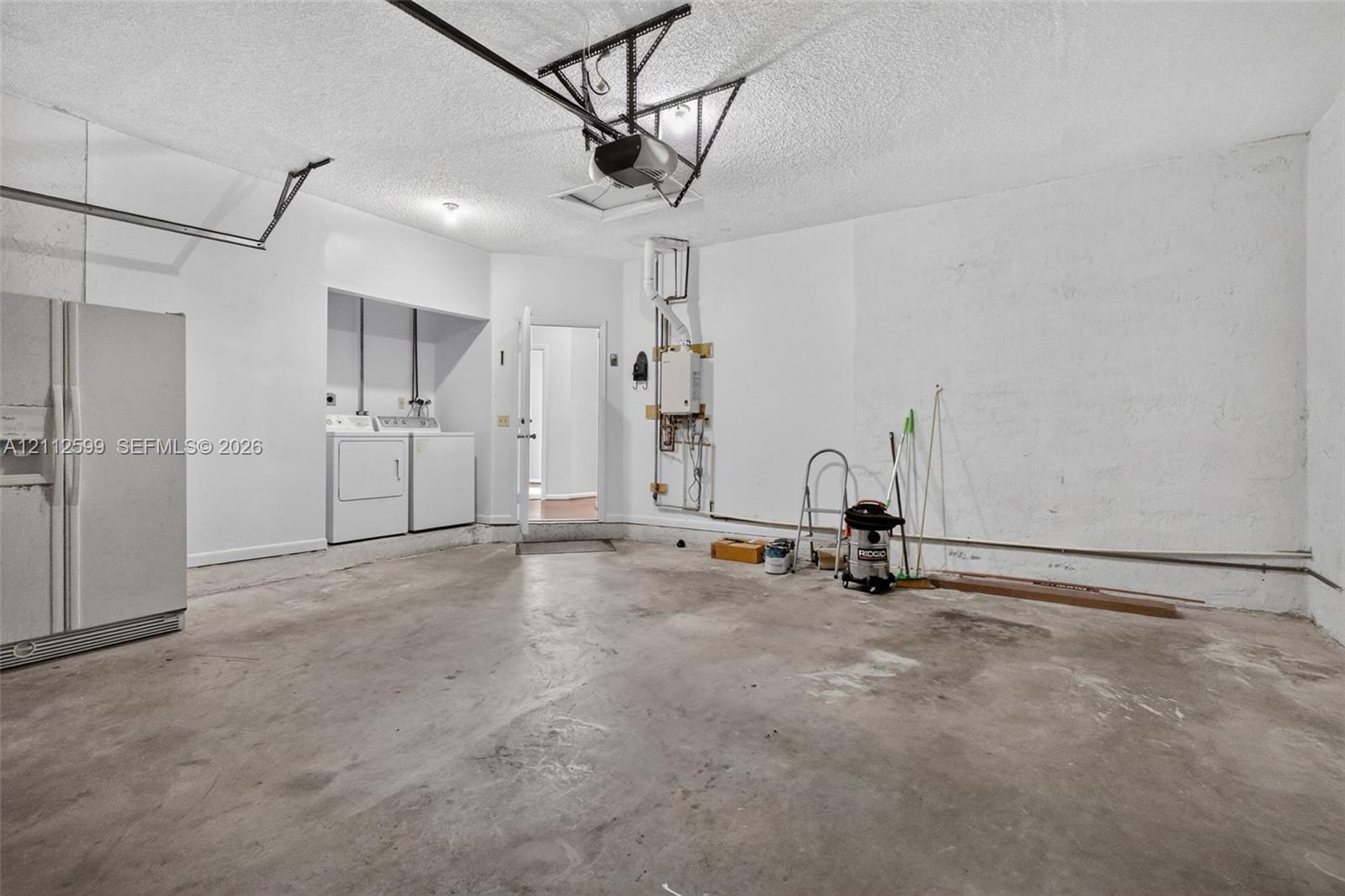 Garage featuring concrete flooring, built-in laundry hookups, and a tankless water heater