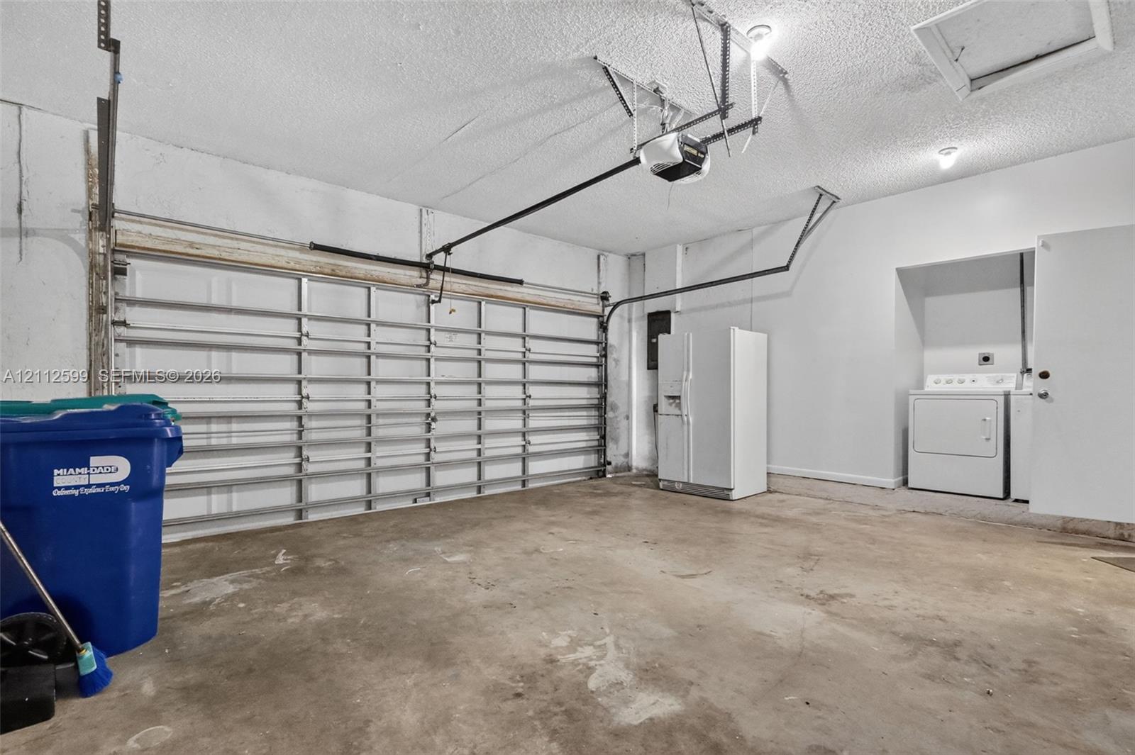 Enclosed two-car garage featuring a sectional overhead door, automatic door opener, concrete flooring, and an integrated laundry utility area