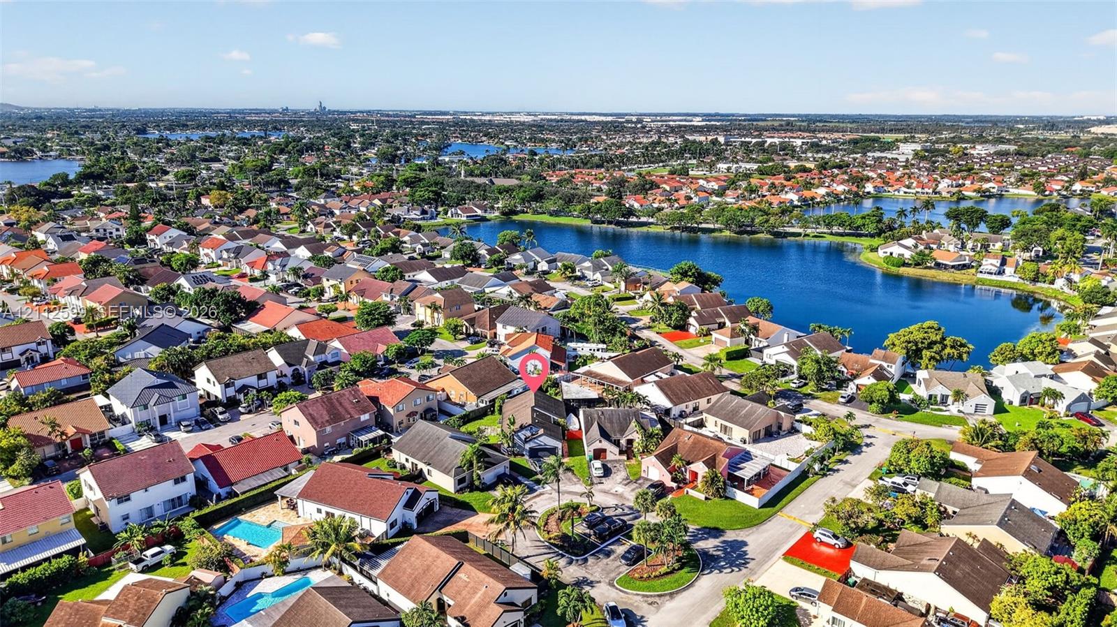 Aerial perspective featuring a residential property situated in a suburban neighborhood with water frontage and mature landscaping