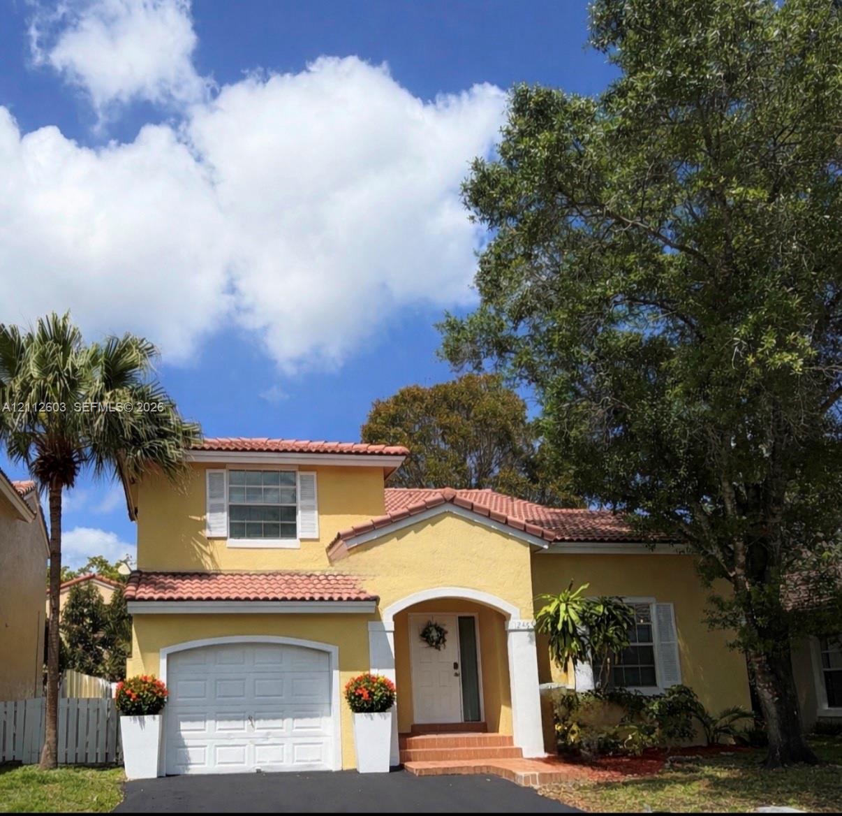 Stucco exterior featuring a terracotta tile roof, arched entryway, single-car garage and driveway for additional 2 cars Stucco exterior featuring a terracotta tile roof, arched entryway, single-car garage and driveway for additional 2 cars