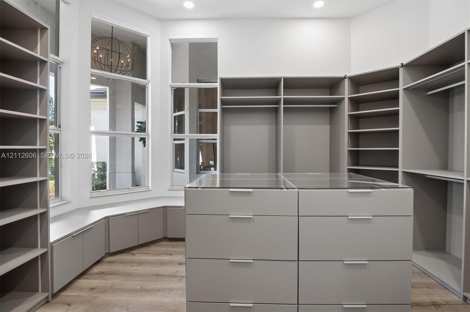 Custom built-in storage system featuring floor-to-ceiling shelving, hanging rods, and a central island with glass-top drawers