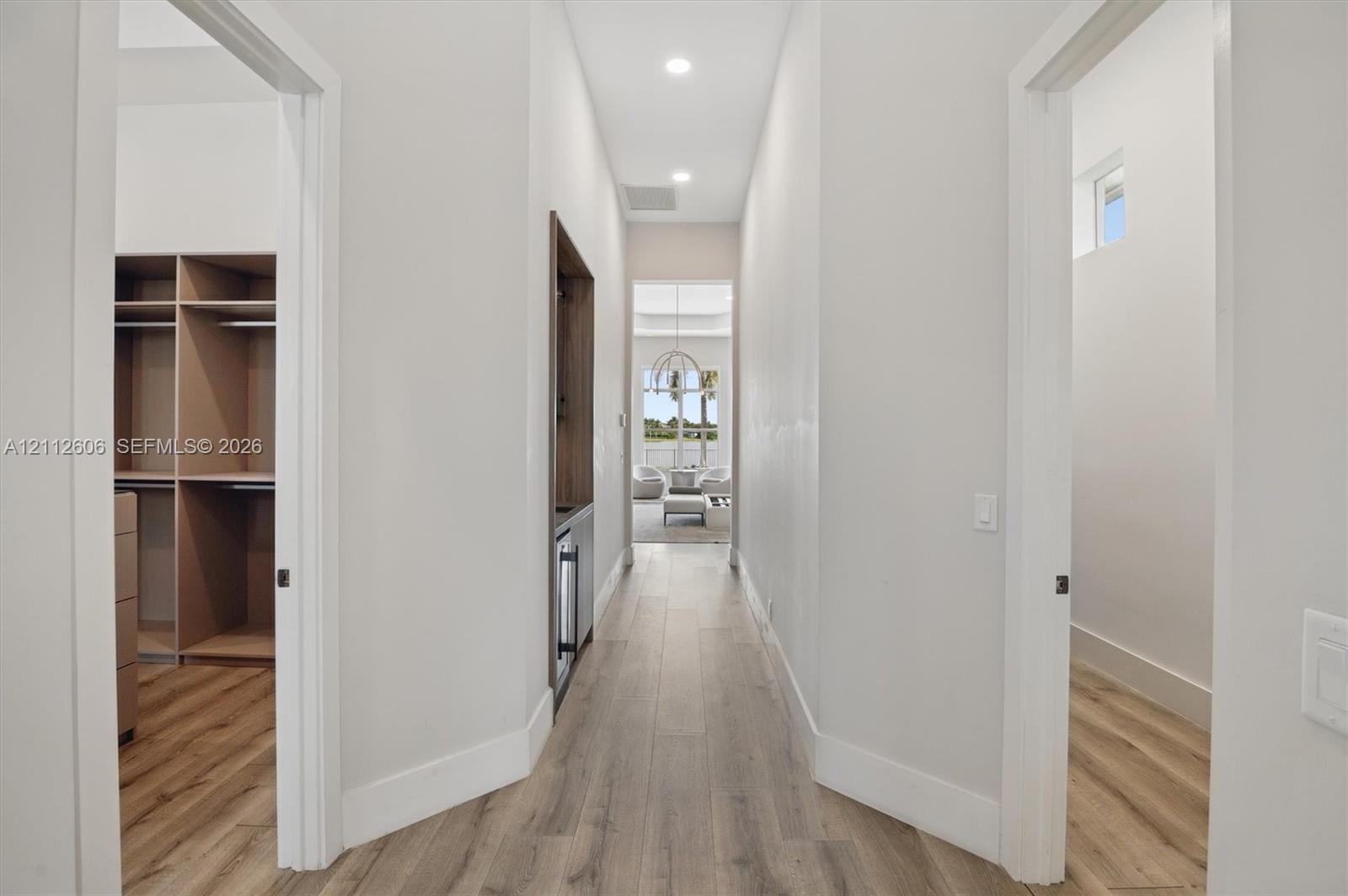 Hallway featuring wood-finish flooring, recessed lighting, built-in cabinetry with integrated beverage refrigeration, and custom-fitted closet shelving
