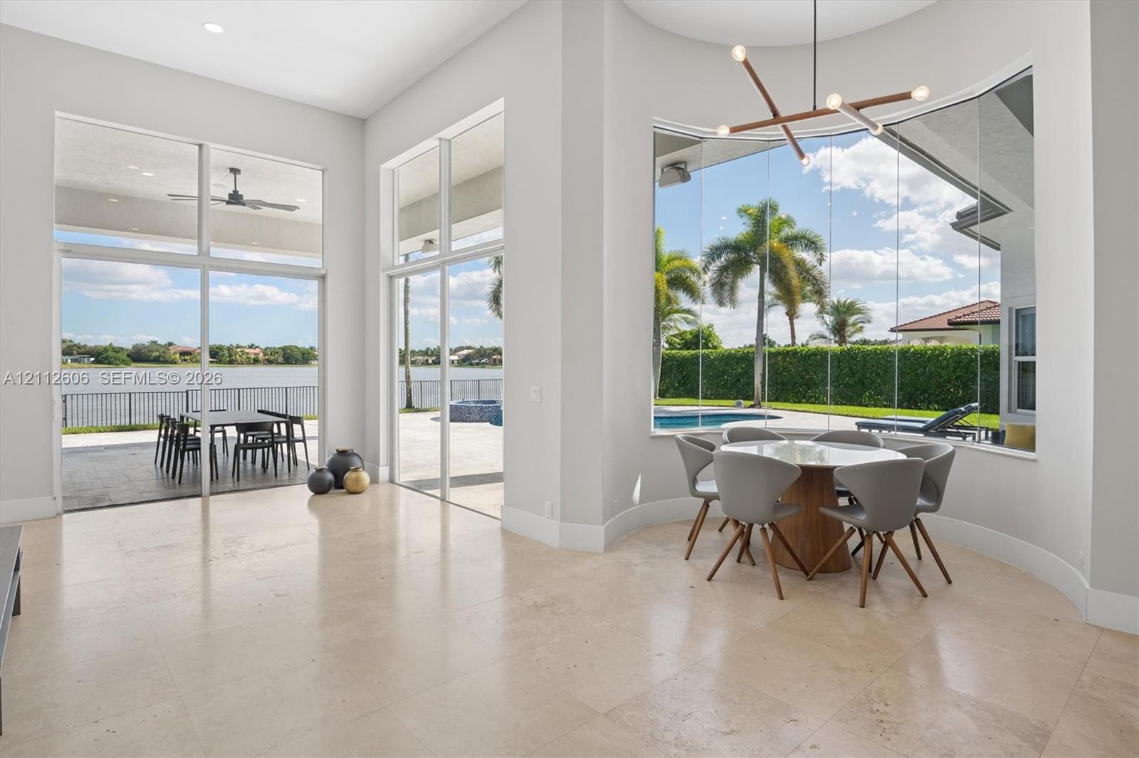 Open-concept space featuring oversized tile flooring, floor-to-ceiling glass windows, sliding glass doors, and a contemporary geometric chandelier