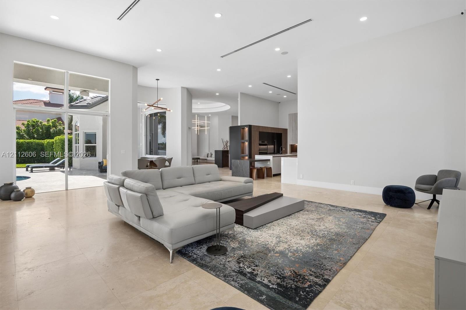 Open-concept living space featuring high ceilings, recessed lighting, large-format tile flooring, and expansive floor-to-ceiling glass sliding doors