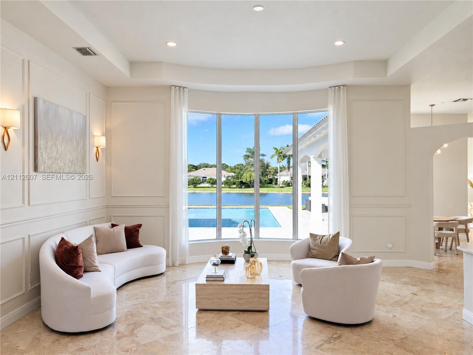 Formal living space featuring a bay window, wall molding, recessed ceiling lighting, wall-mounted light fixtures, and stone flooring