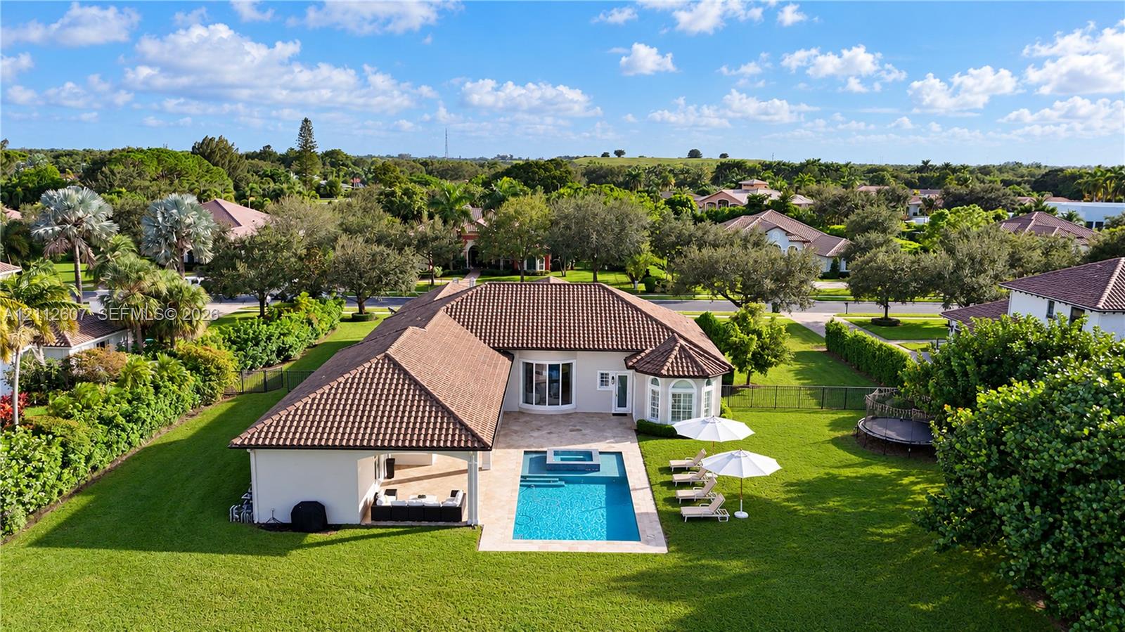Single-story residence featuring a tile roof, covered patio, integrated swimming pool with spa, and expansive lawn