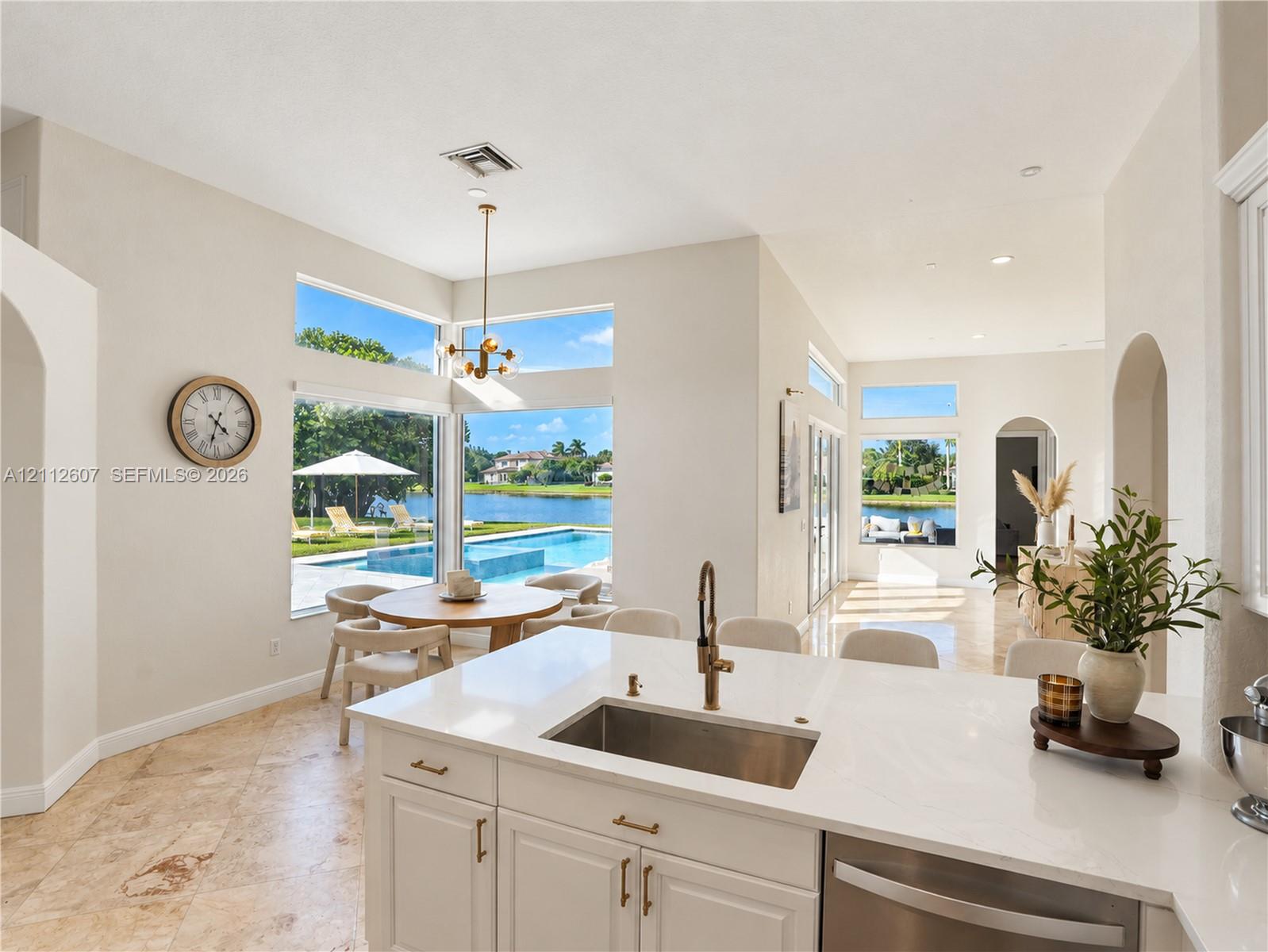 Kitchen featuring stone flooring, white cabinetry, a quartz countertop, an undermount stainless steel sink with a metallic faucet, and expansive floor-to-ceiling windows