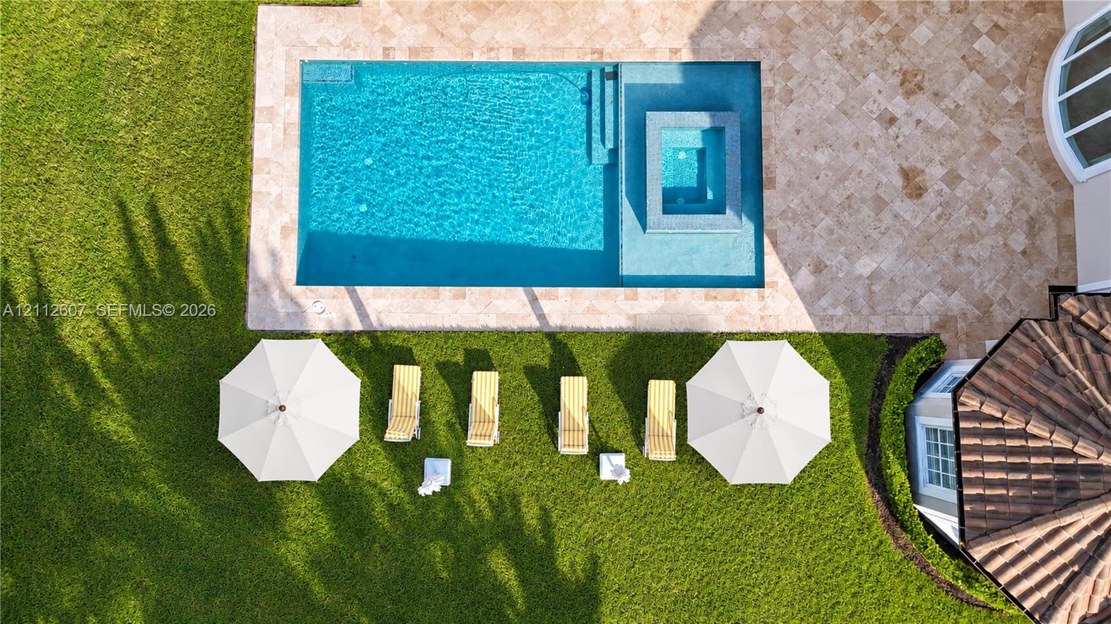 Rectangular swimming pool featuring a spillover spa and stone-paver decking, set within a manicured lawn