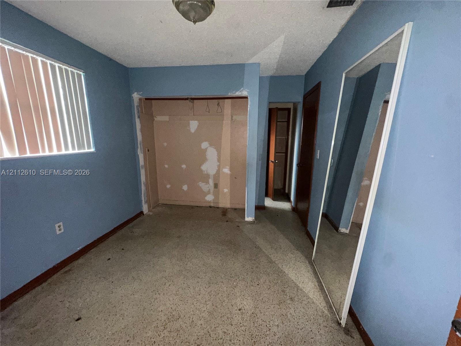 Room featuring speckled terrazzo flooring, vertical window blinds, and solid-core interior doors