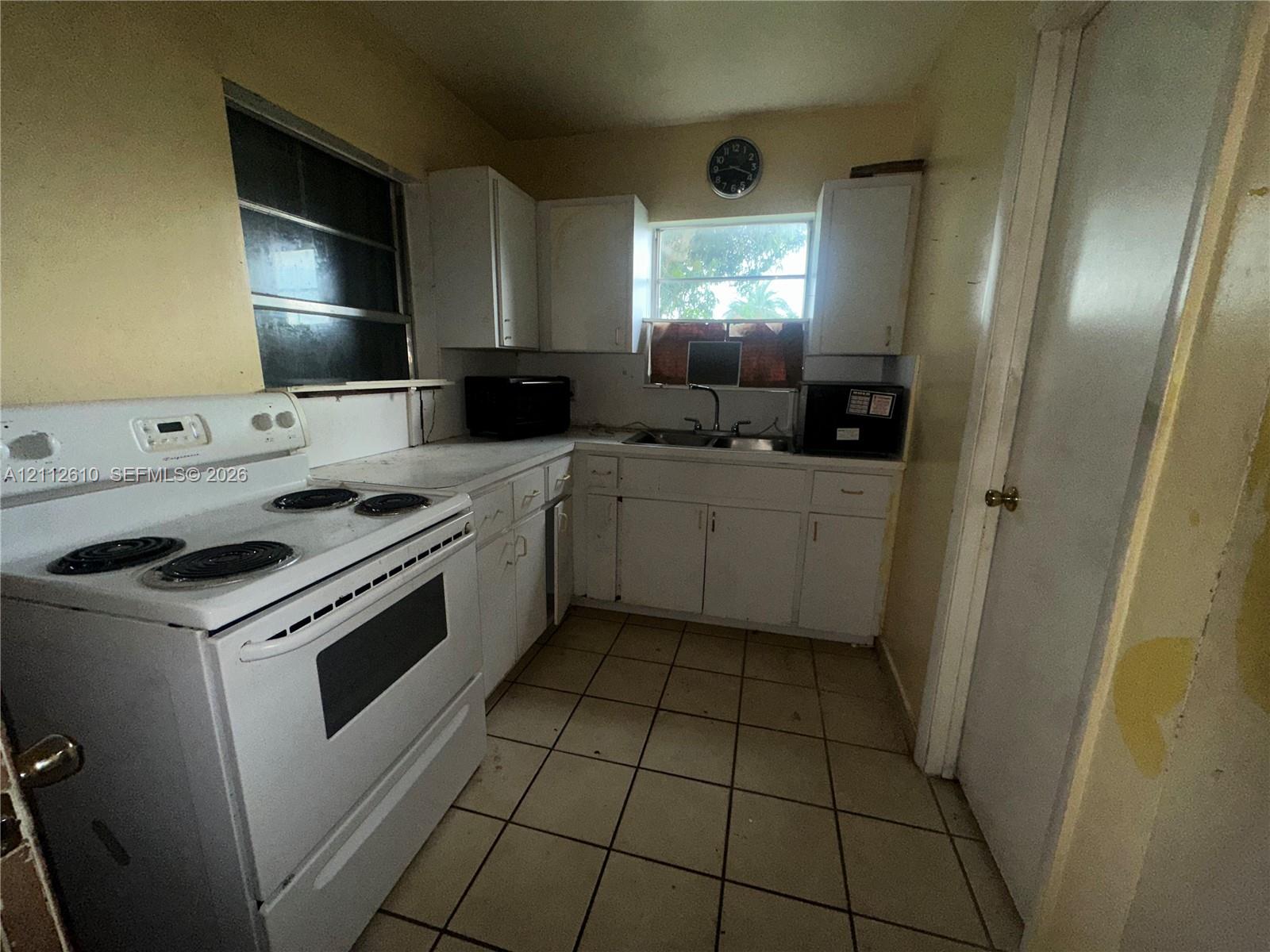 Kitchen featuring white cabinetry, a white electric range, a double-basin sink, and tile flooring
