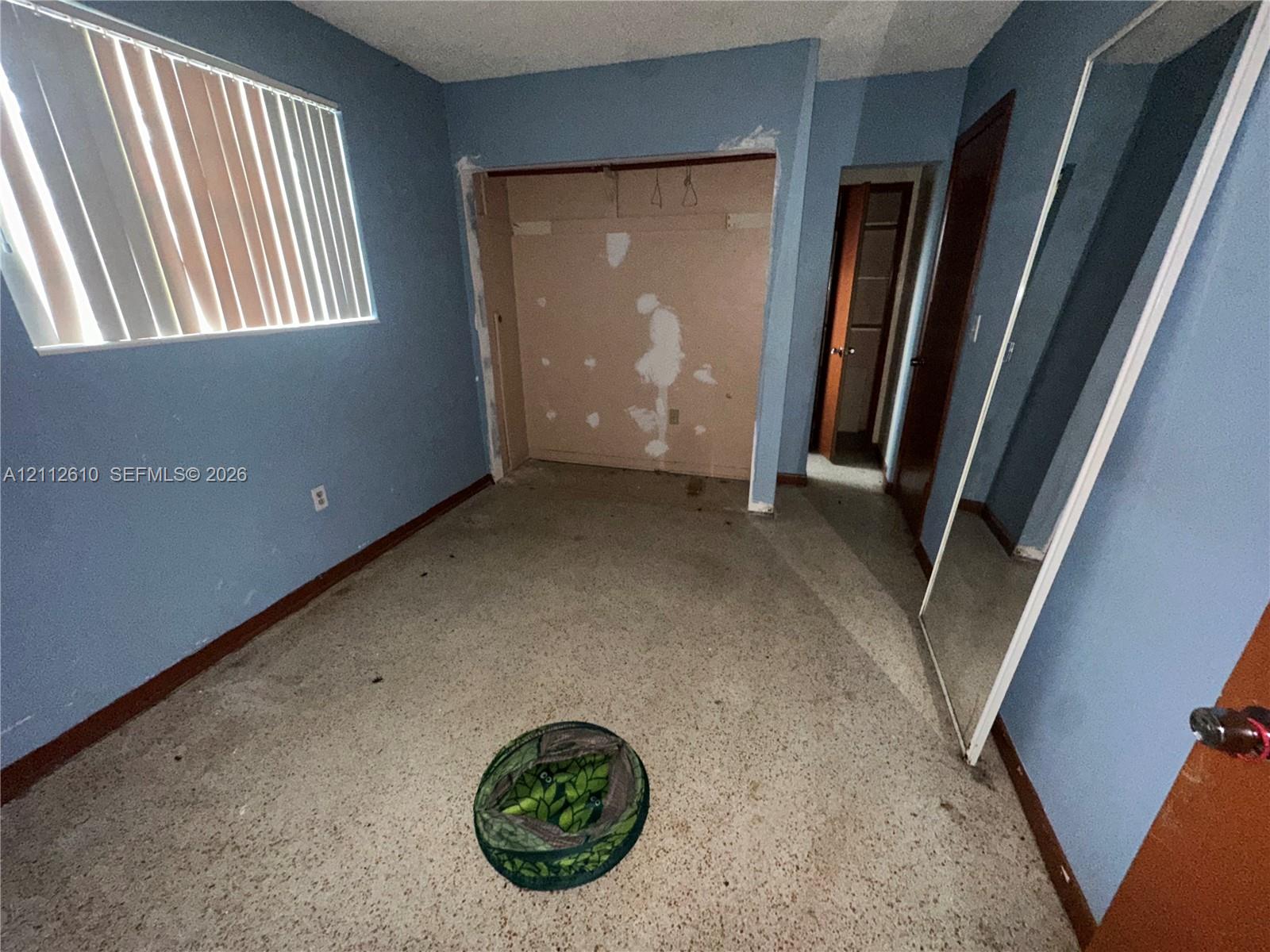 Interior room featuring a window with vertical blinds, closet space, and terrazzo flooring