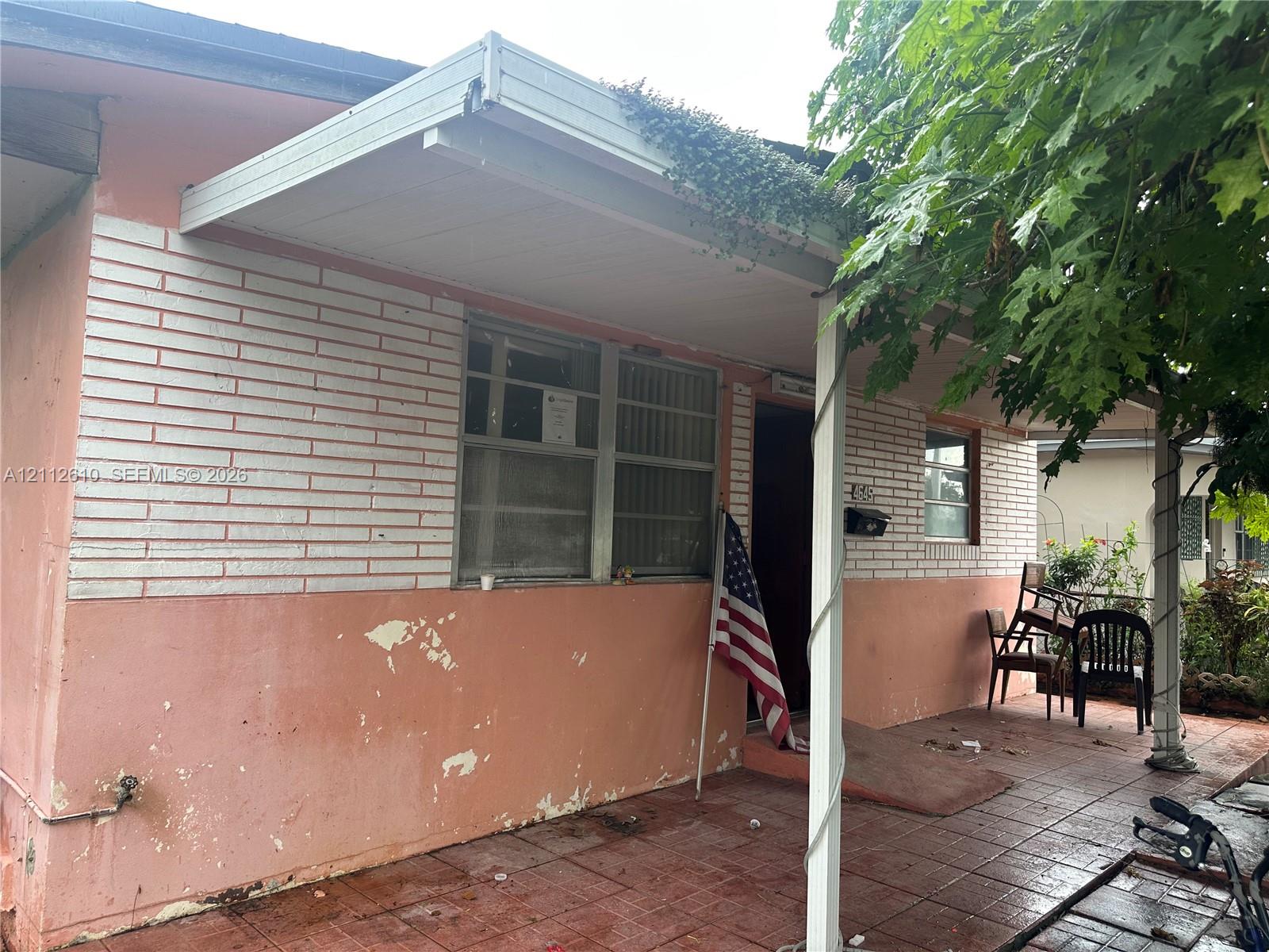 Exterior facade featuring painted brick masonry, a covered porch, and tile patio flooring
