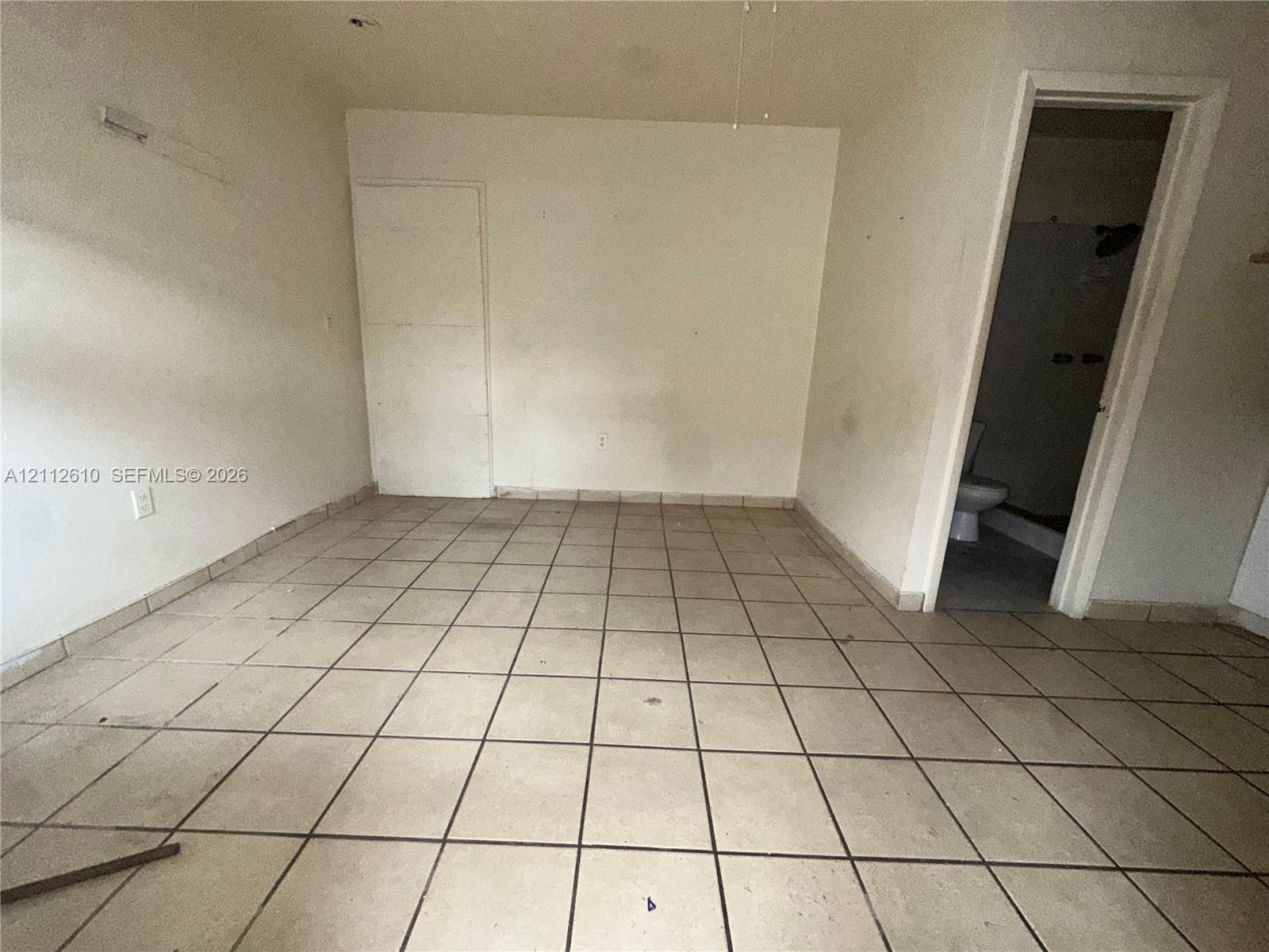 Interior room featuring light-toned ceramic tile flooring and a doorway leading to a tiled bath area