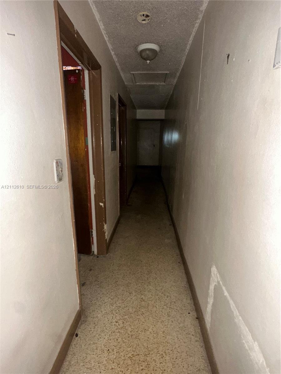 Hallway featuring textured ceiling, flush-mount light fixture, and tile flooring