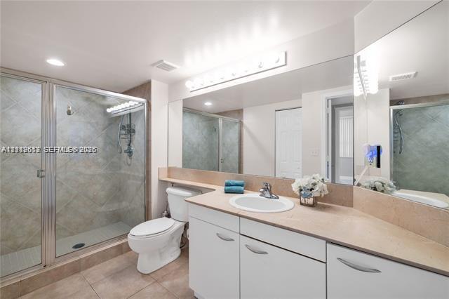 Full-width vanity with a neutral solid-surface countertop and recessed basin, glass-enclosed shower with tile surround, and expansive wall-to-wall mirror