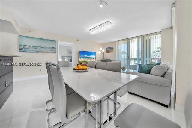 Open-concept living space featuring high-gloss tile flooring, floor-to-ceiling sliding glass doors, and a rectangular, modern tiered crystal ceiling fixture